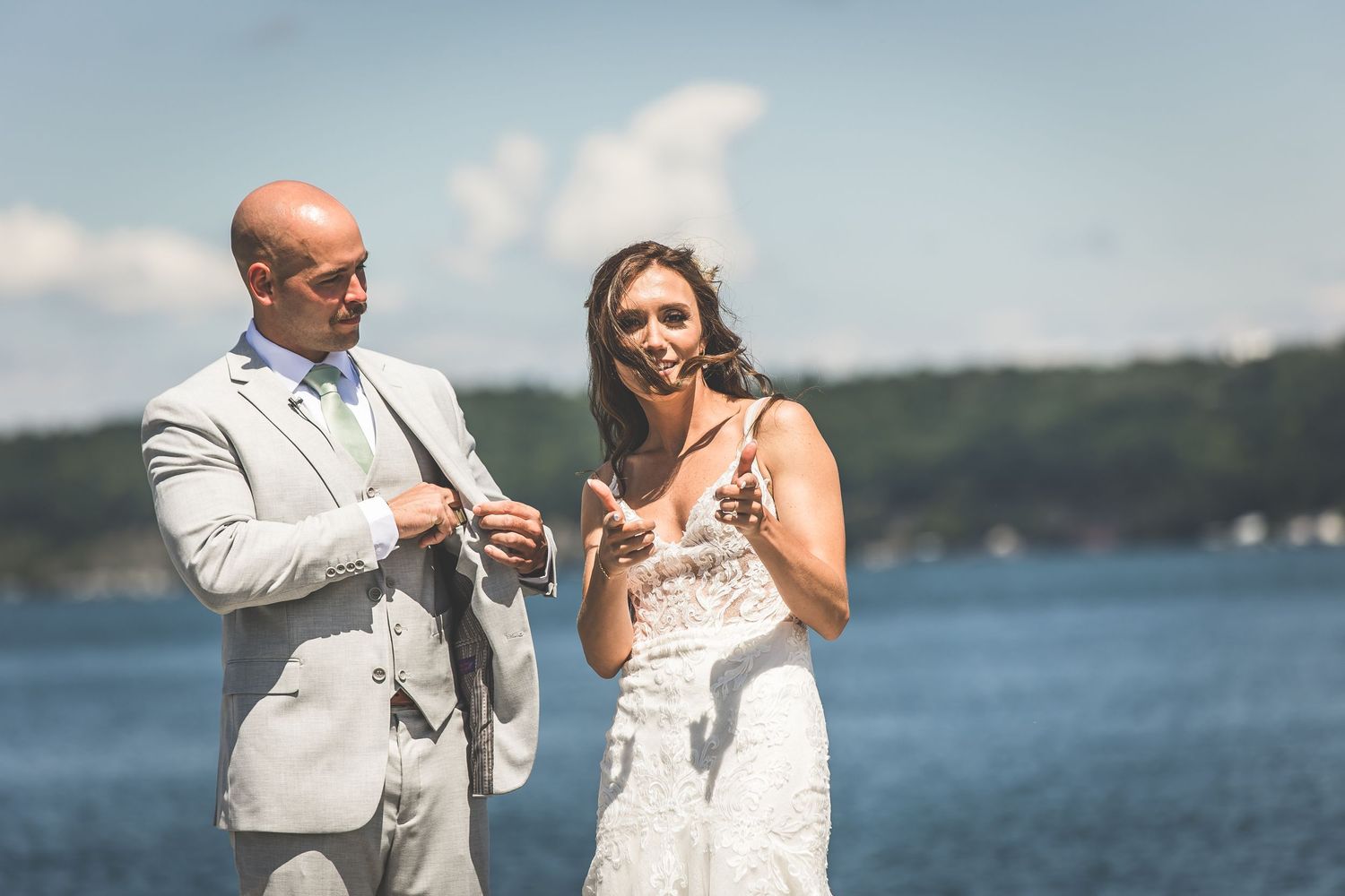 A joyful wedding couple shares a laugh during their lakeside photo session.