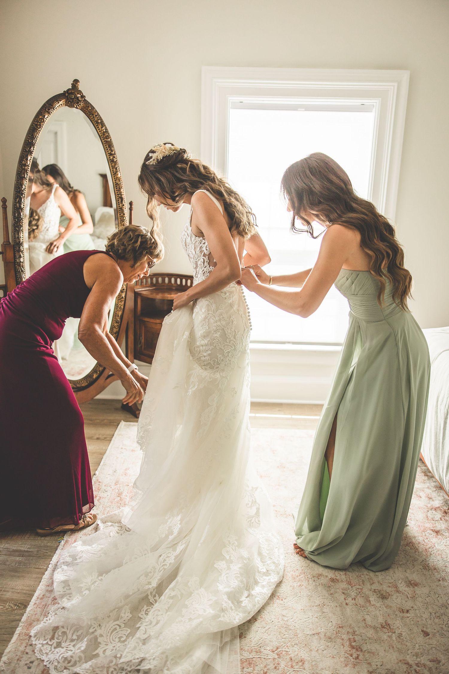 Wedding party helps adjust the bride's dress train on a light carpet.