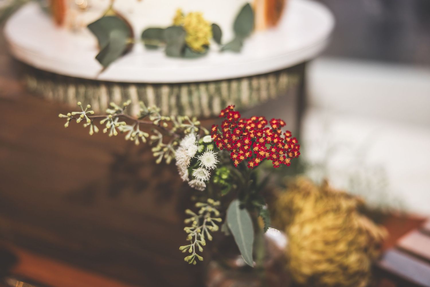 Wedding table decorations featuring greenery, berries and yellow floral accents.