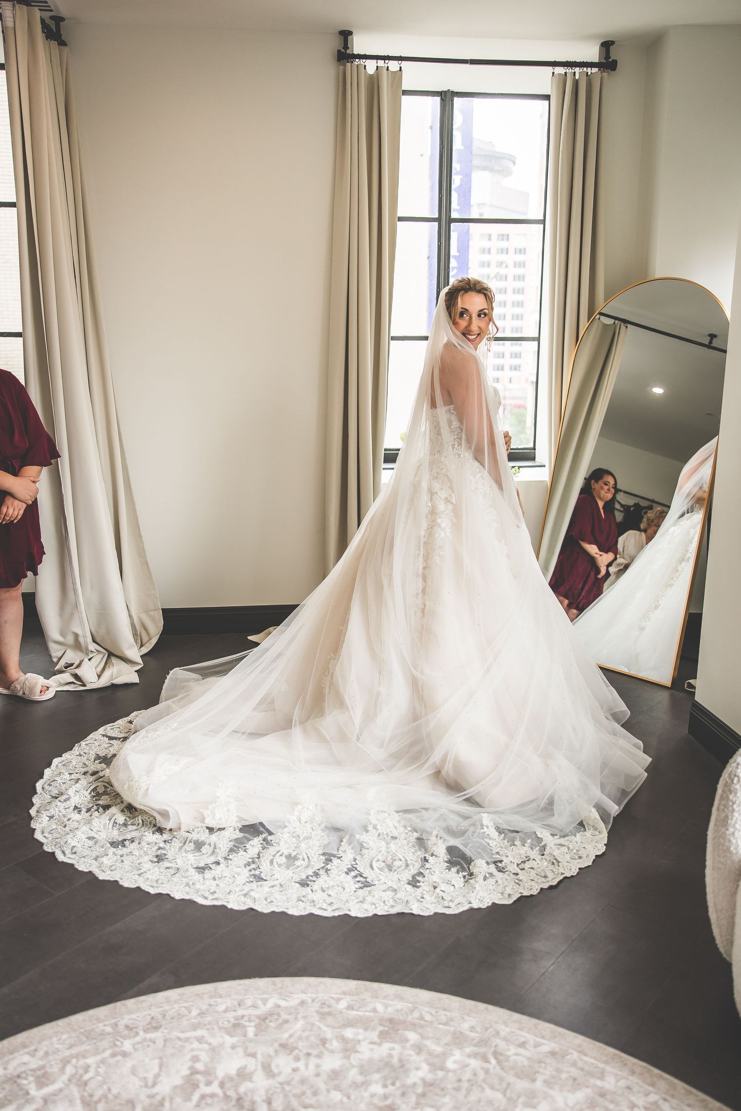 Stunning wedding dress with long lace train displayed in bridal suite with natural window light.