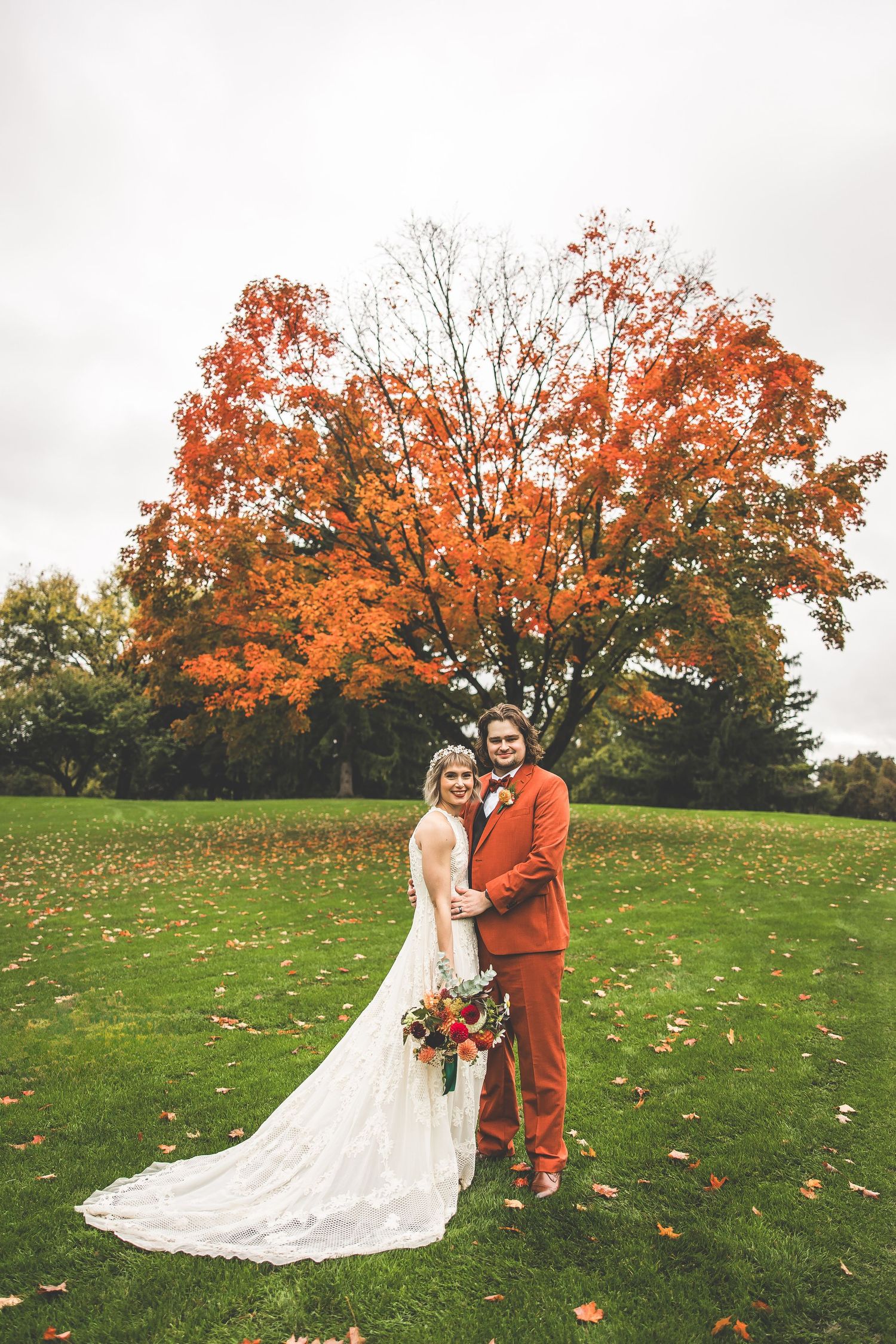 Elegant wedding photo with stunning fall foliage and lush green lawn.