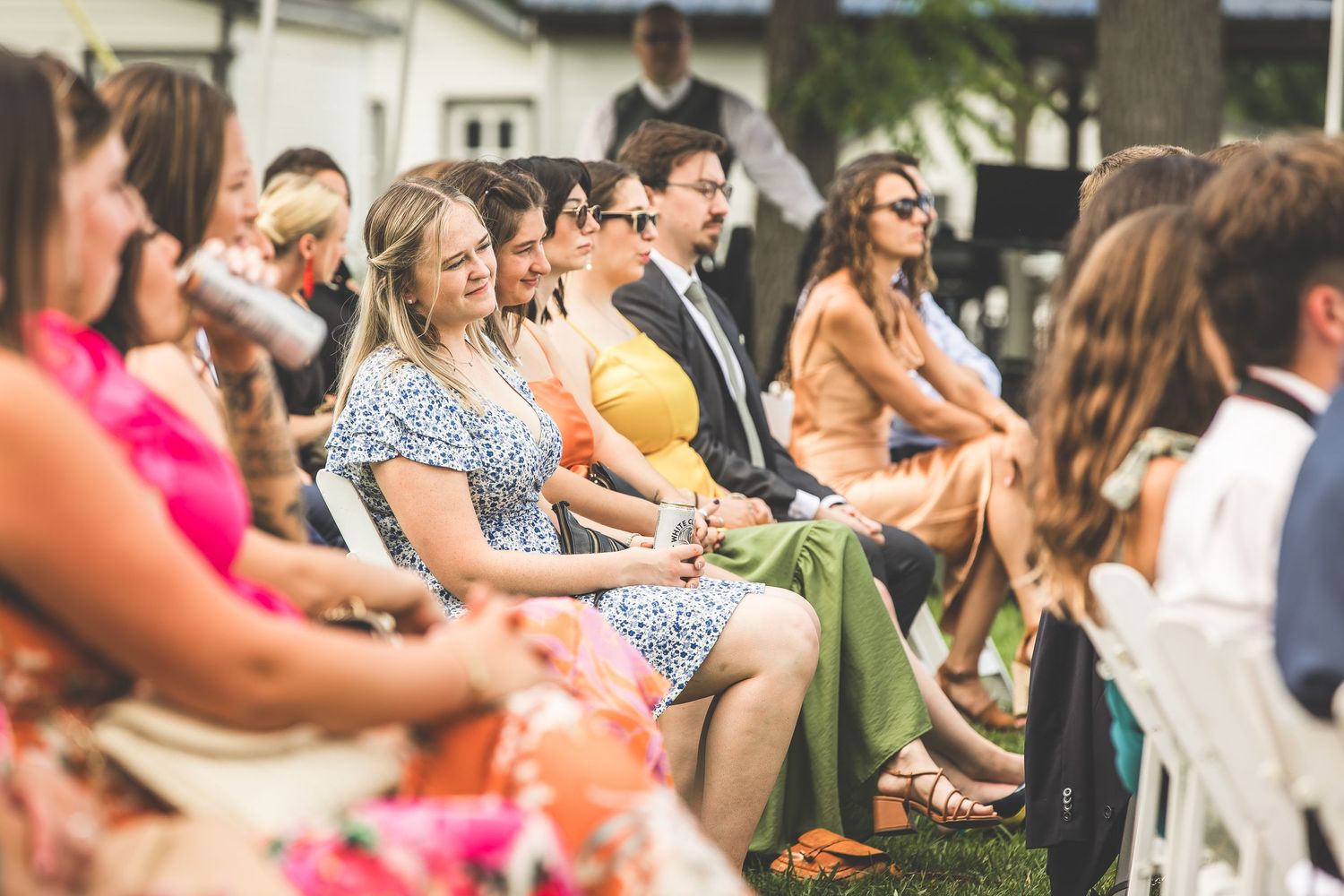 Wedding guests in summer attire enjoying outdoor celebration by the water.