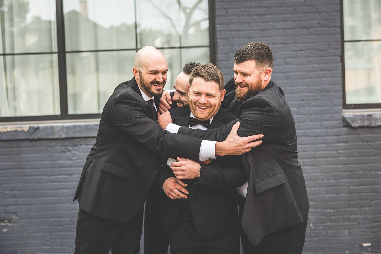 Groomsmen share a candid laughing moment together during wedding photos.