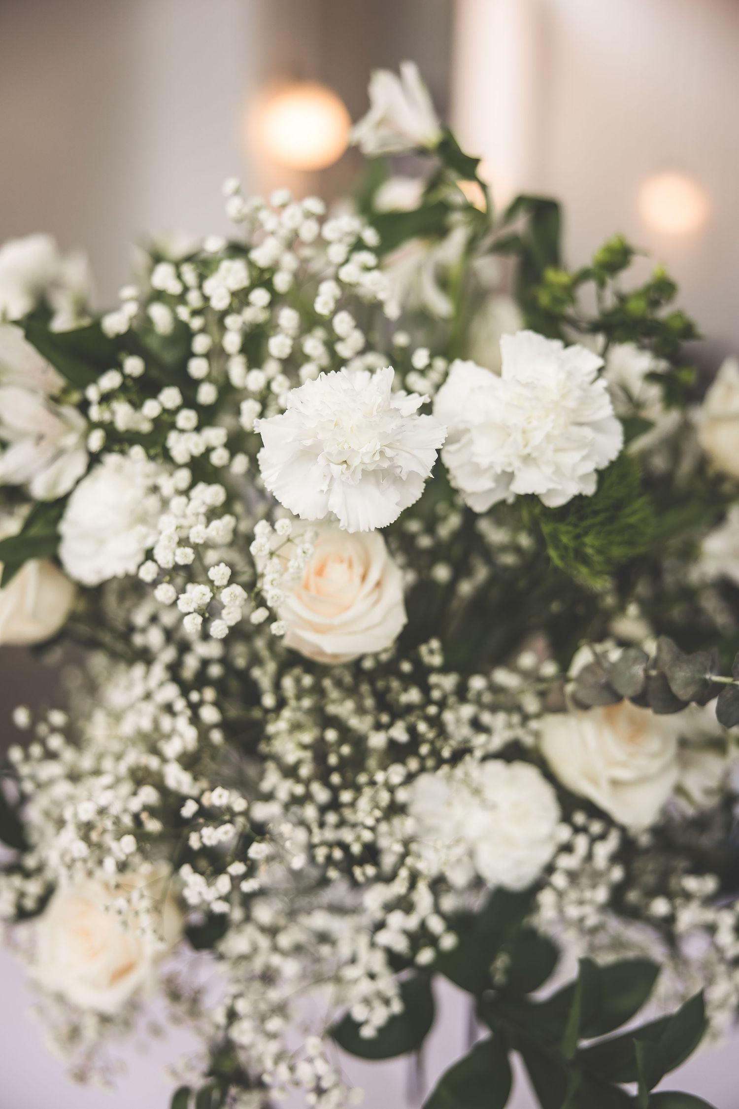 Elegant white roses and baby's breath floral arrangements with soft lighting create a romantic wedding atmosphere.