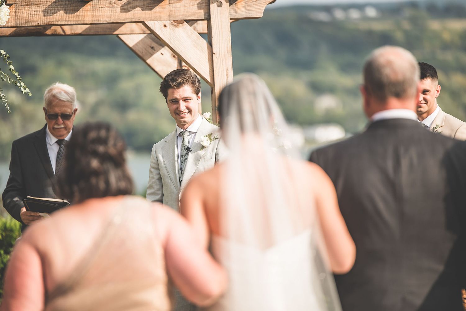 Wedding guests mingle during outdoor reception with scenic hillside views.