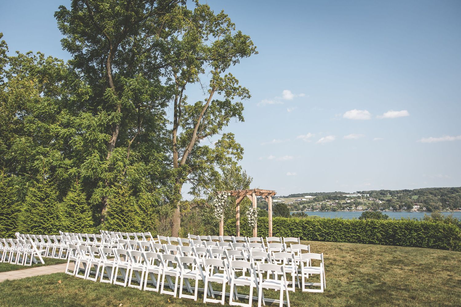 White wedding ceremony chairs lined up on a hilltop overlooking scenic landscape.