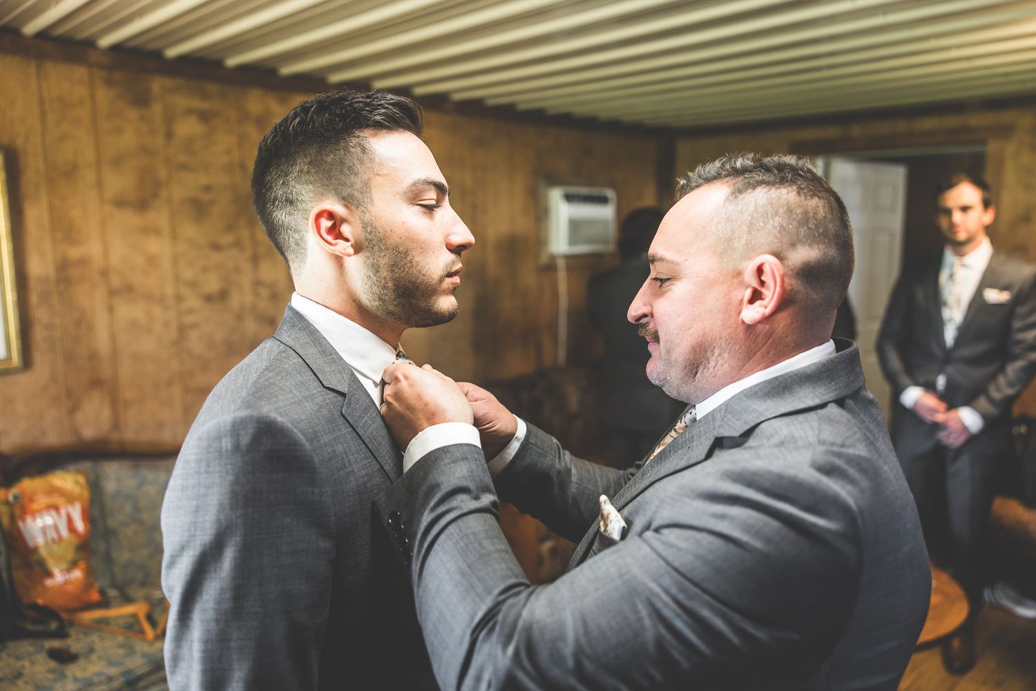 Tender moment between two people adjusting formal attire before ceremony.
