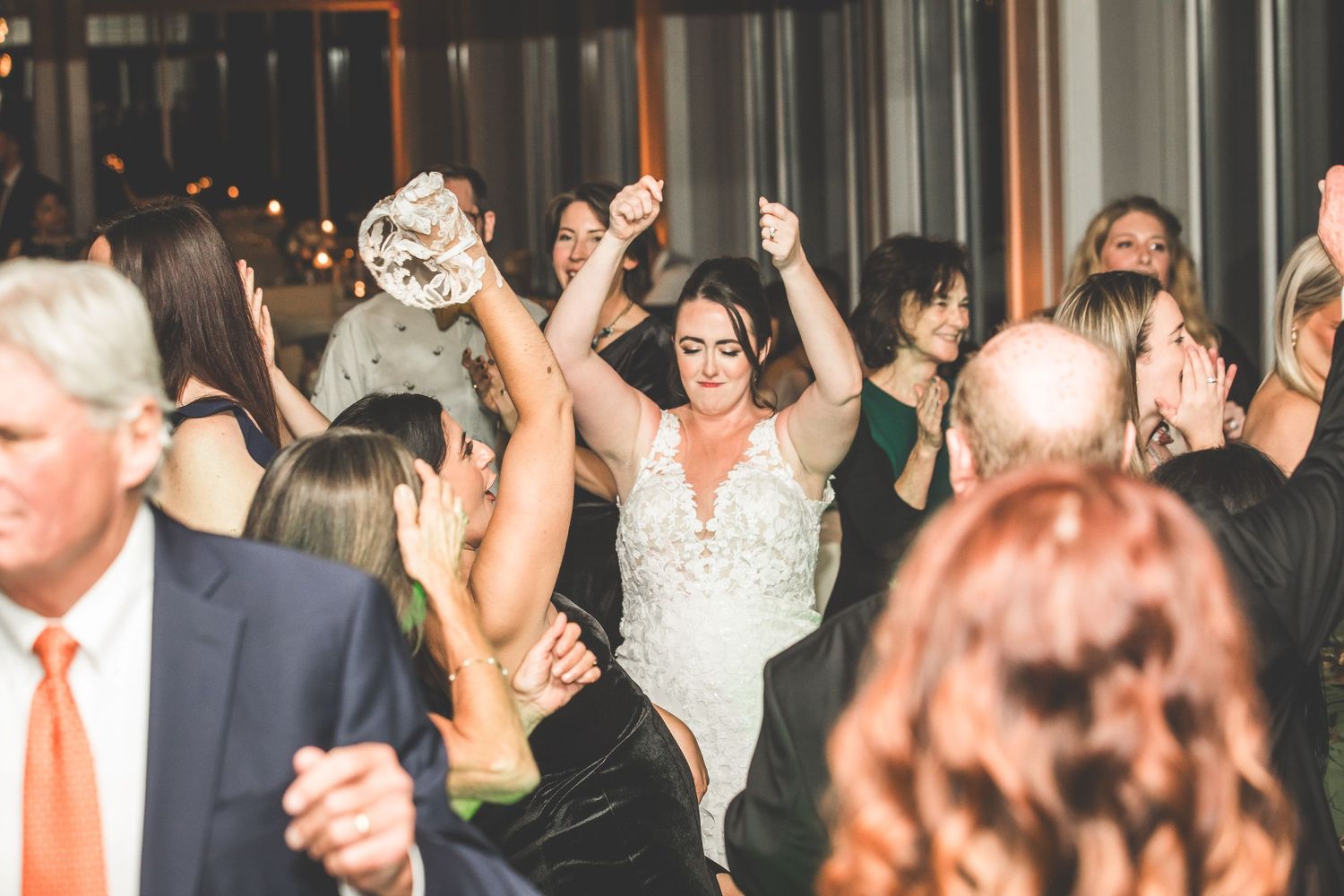 Joyful celebration on a packed wedding reception dance floor with guests in formal attire.