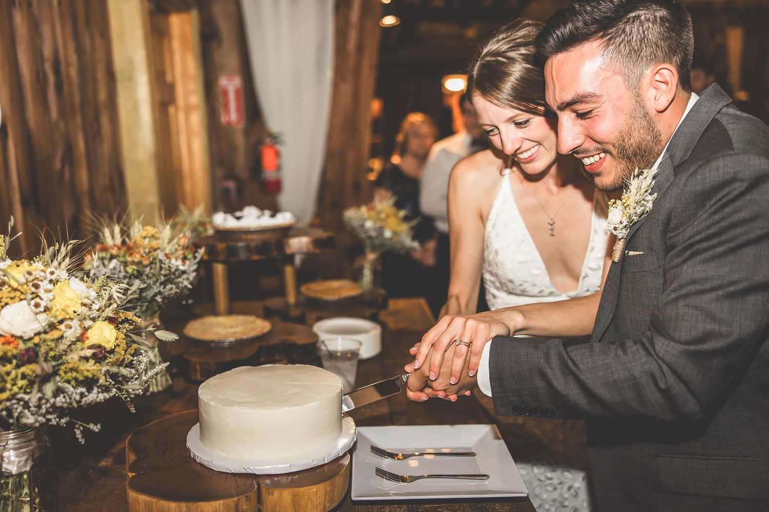 Couple sharing intimate moment at dessert table during rustic barn wedding reception.