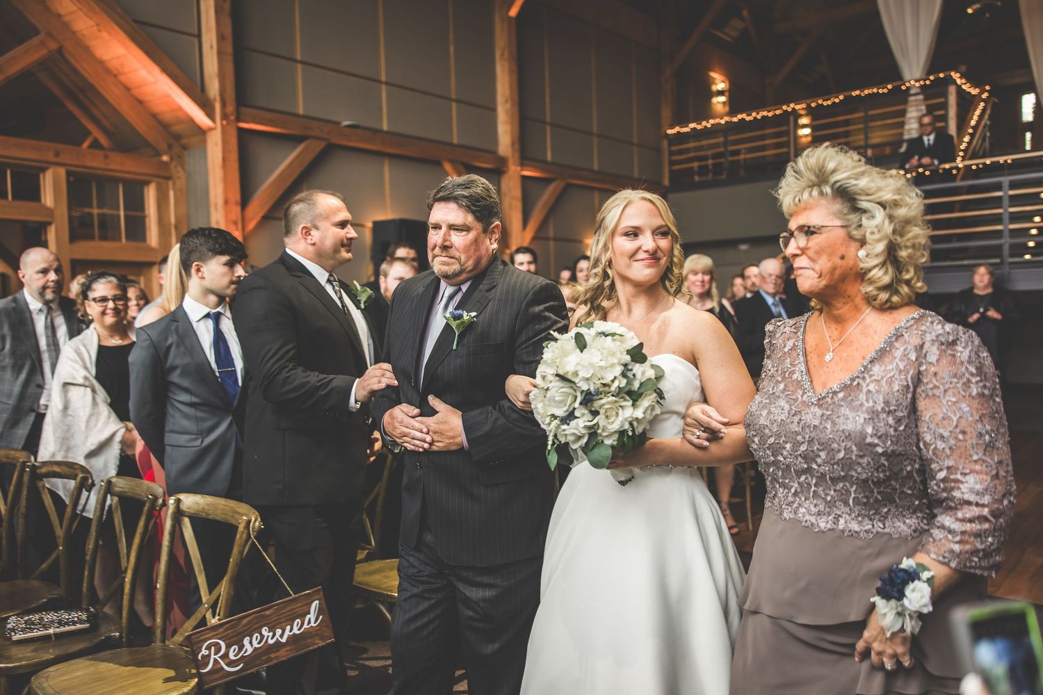Wedding celebration in a rustic venue with exposed wooden beams and elegant white draping.