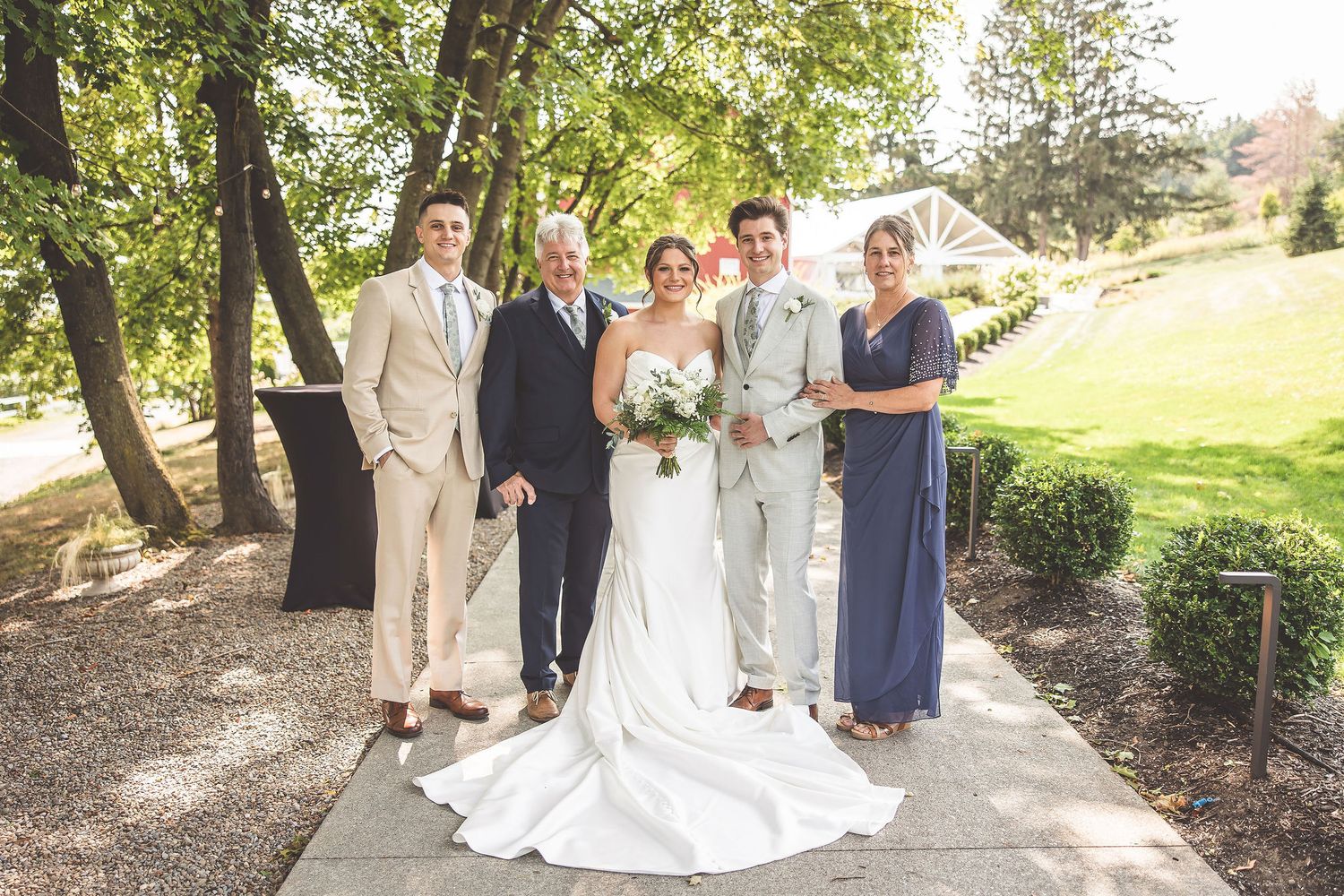 Wedding party stands together on a garden path for formal portraits.