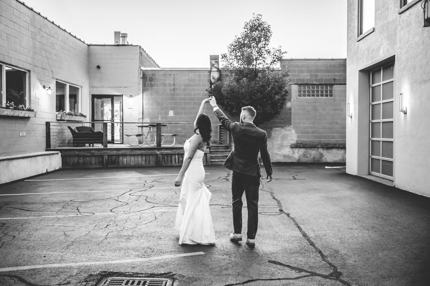 A black and white wedding photo of a couple walking together on a patio.