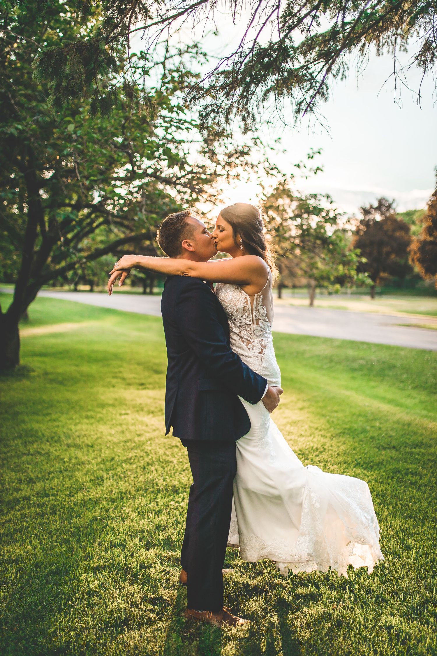 Romantic wedding portraits captured during golden hour on grassy hillside.