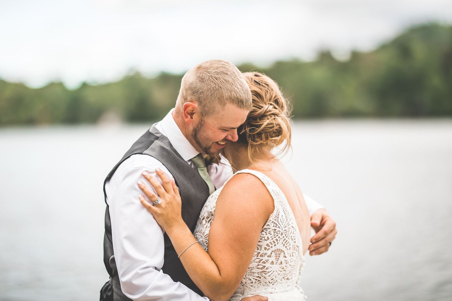 Tender moments between newlyweds captured by the waterfront during golden hour.