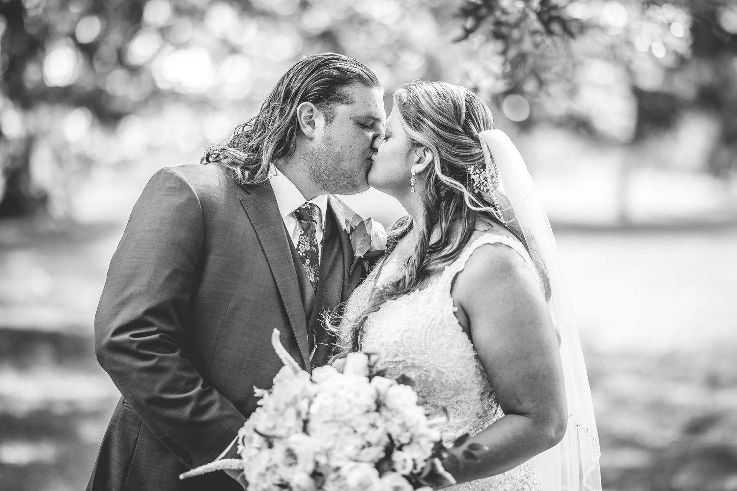 Black and white wedding portrait capturing an intimate kiss between newlyweds.
