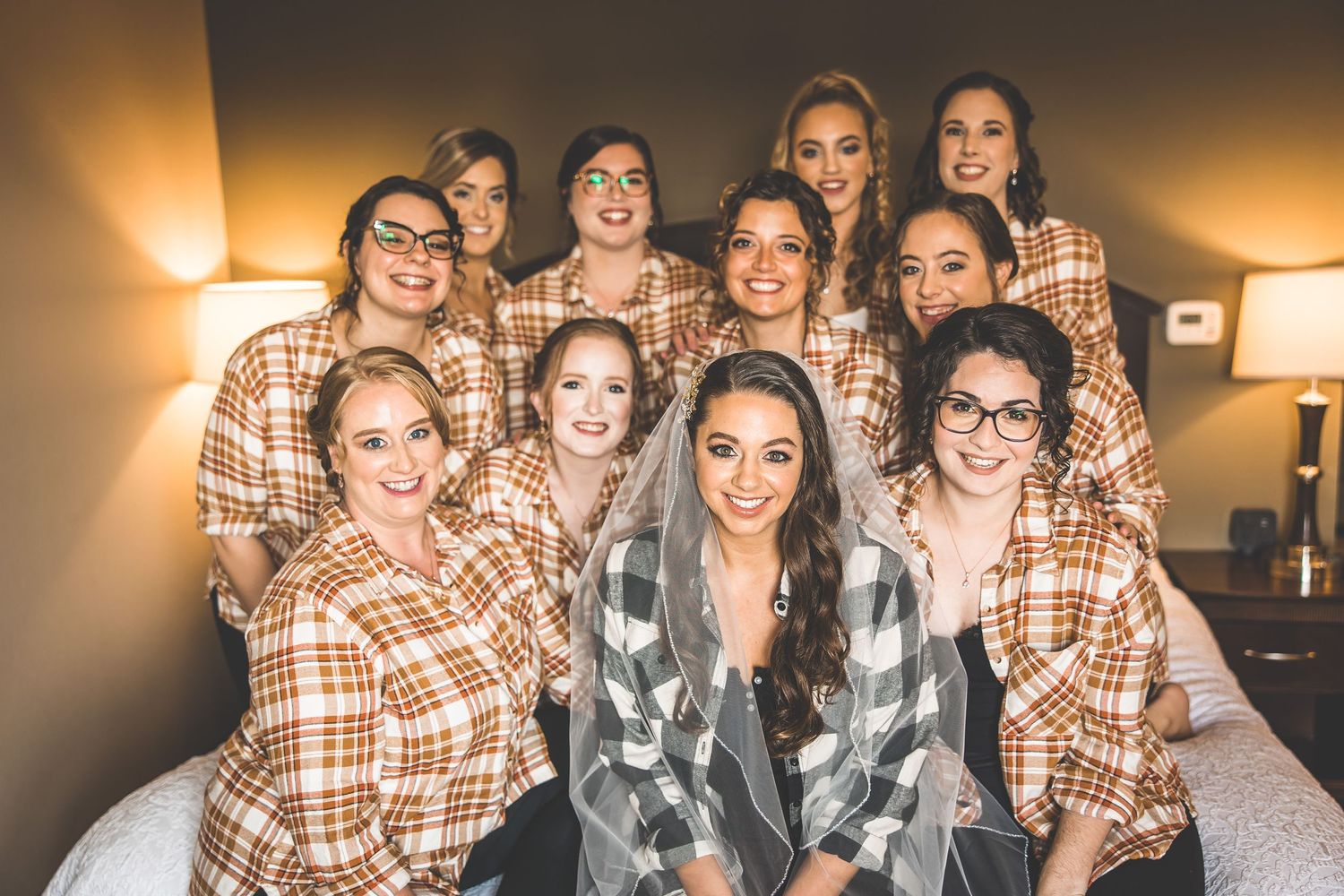 Group wearing matching plaid flannel shirts posing together on a bed.