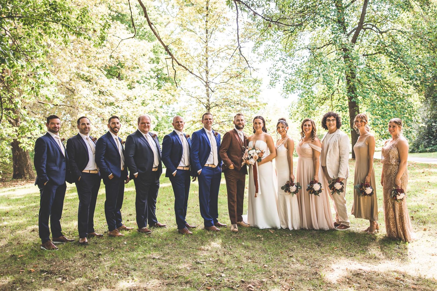 Full wedding party lineup photographed in an outdoor garden setting with natural lighting.