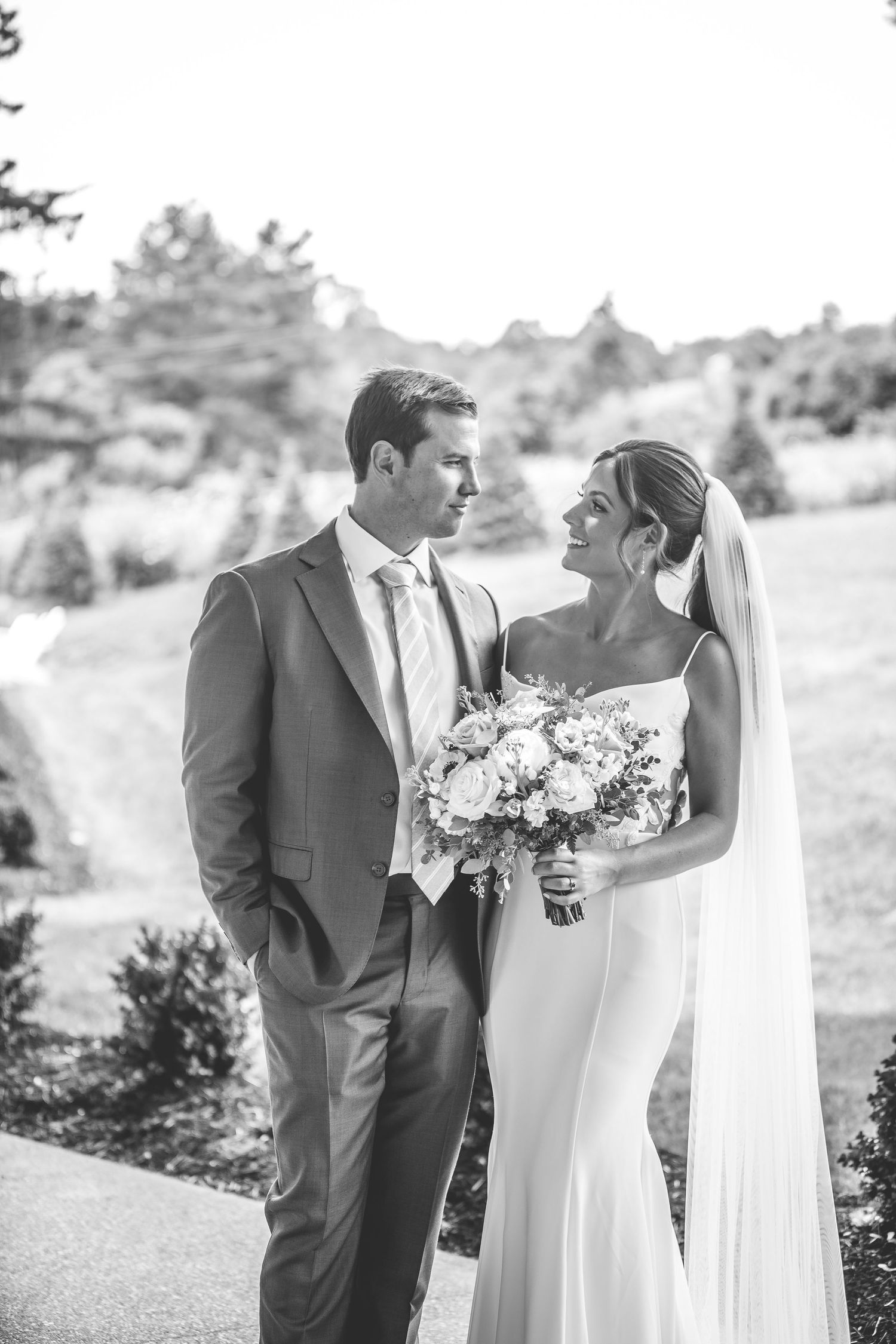 A romantic black and white wedding photo showing a couple sharing an intimate moment outdoors.