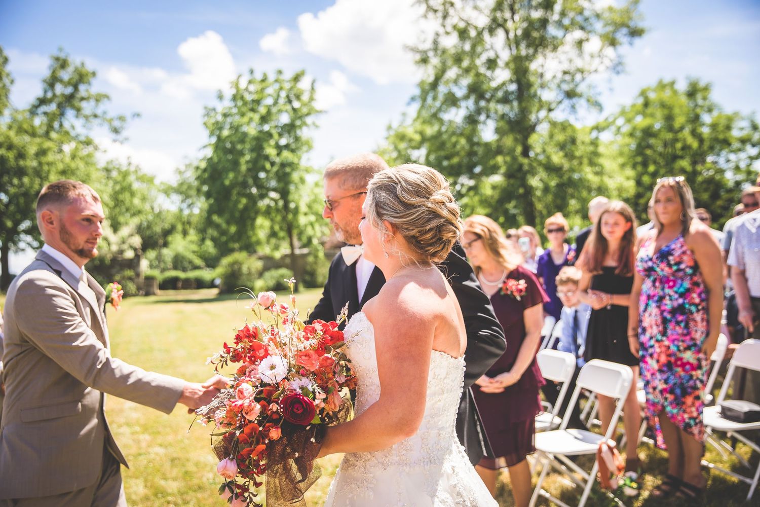 Wedding guests and bridal party mingle during an outdoor summer celebration.