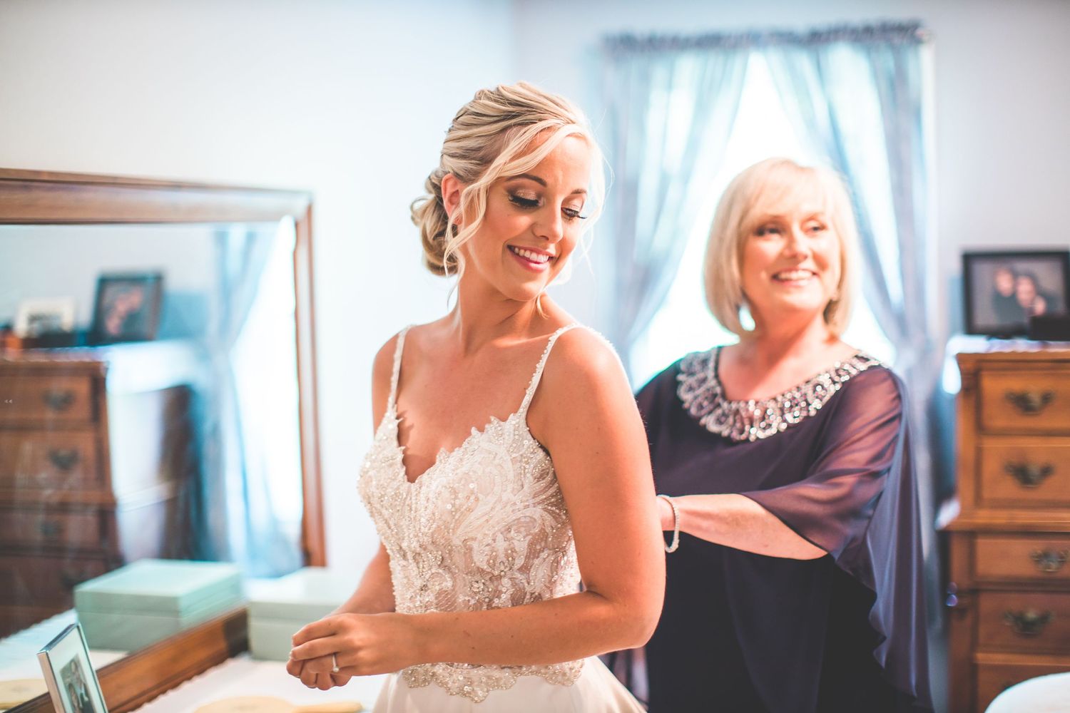 Emotional getting ready moments shared between wedding party members in a bright room.