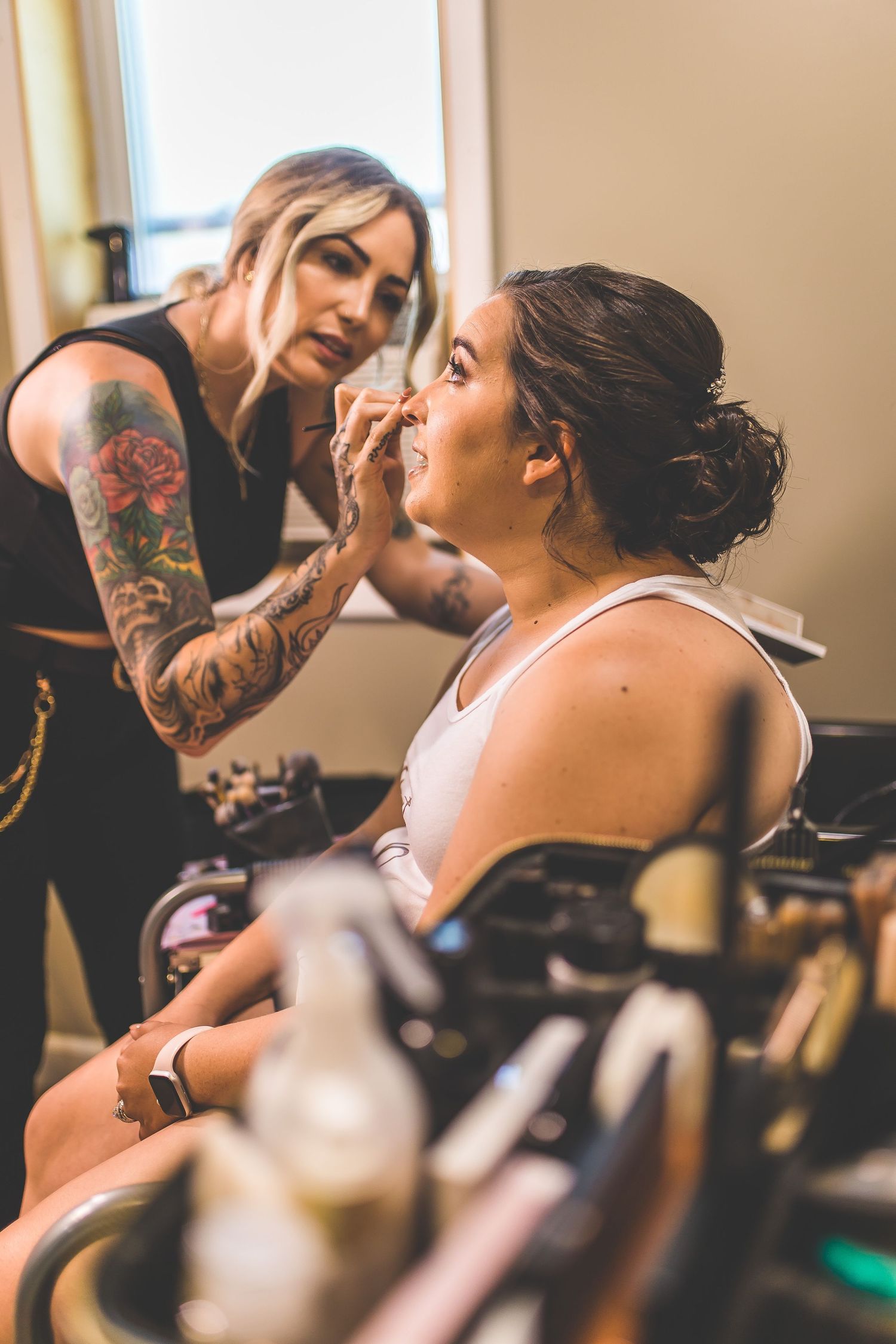 Wedding preparation scene with makeup being applied in warm natural lighting.