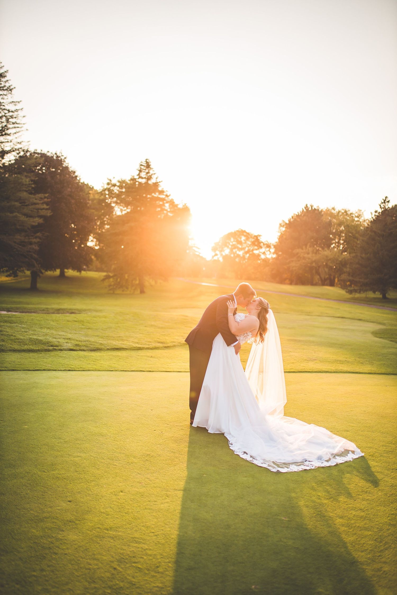 Golden hour wedding portraits on a manicured golf course lawn.