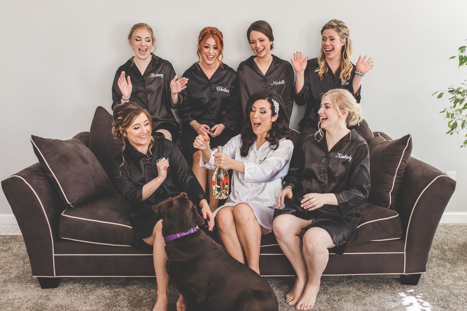 Group lounging on dark brown couch during casual pre-wedding gathering.