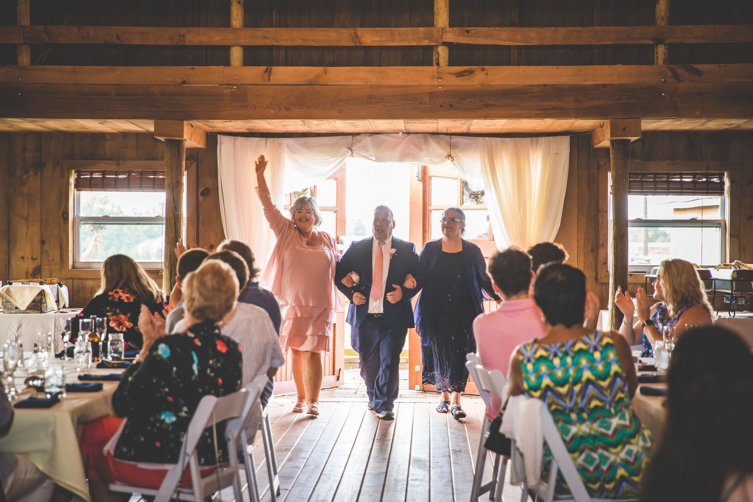 Wedding reception dance floor with guests celebrating inside rustic barn venue.