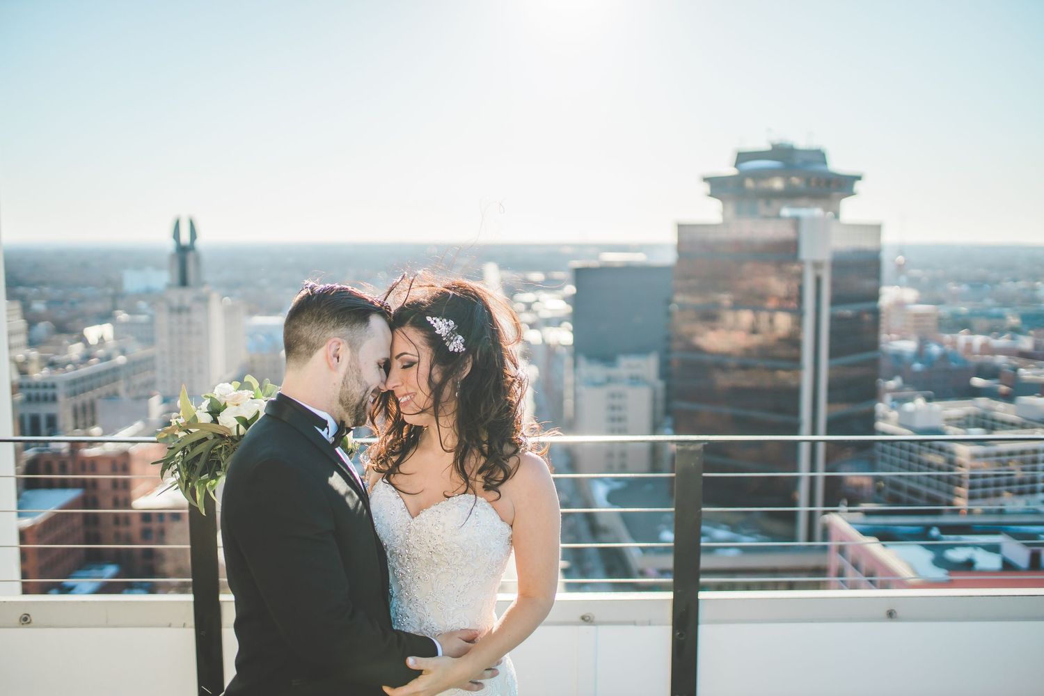 A couple shares an intimate moment on a rooftop with city skyline views.