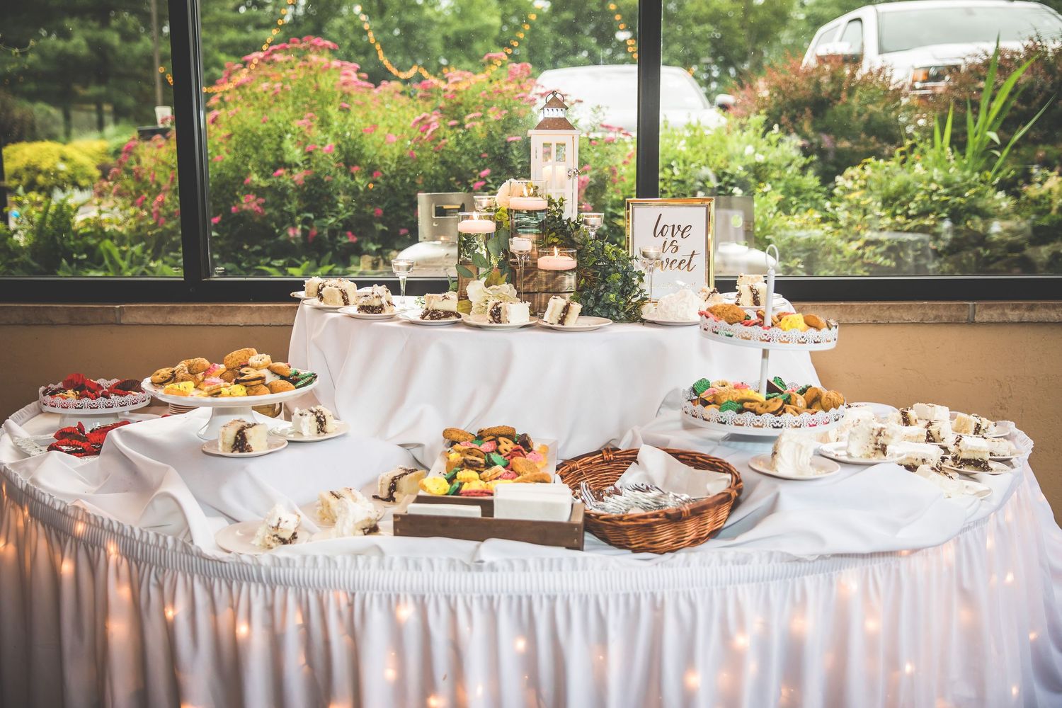 Long buffet table with white linens displaying various appetizers and dishes at a wedding reception.