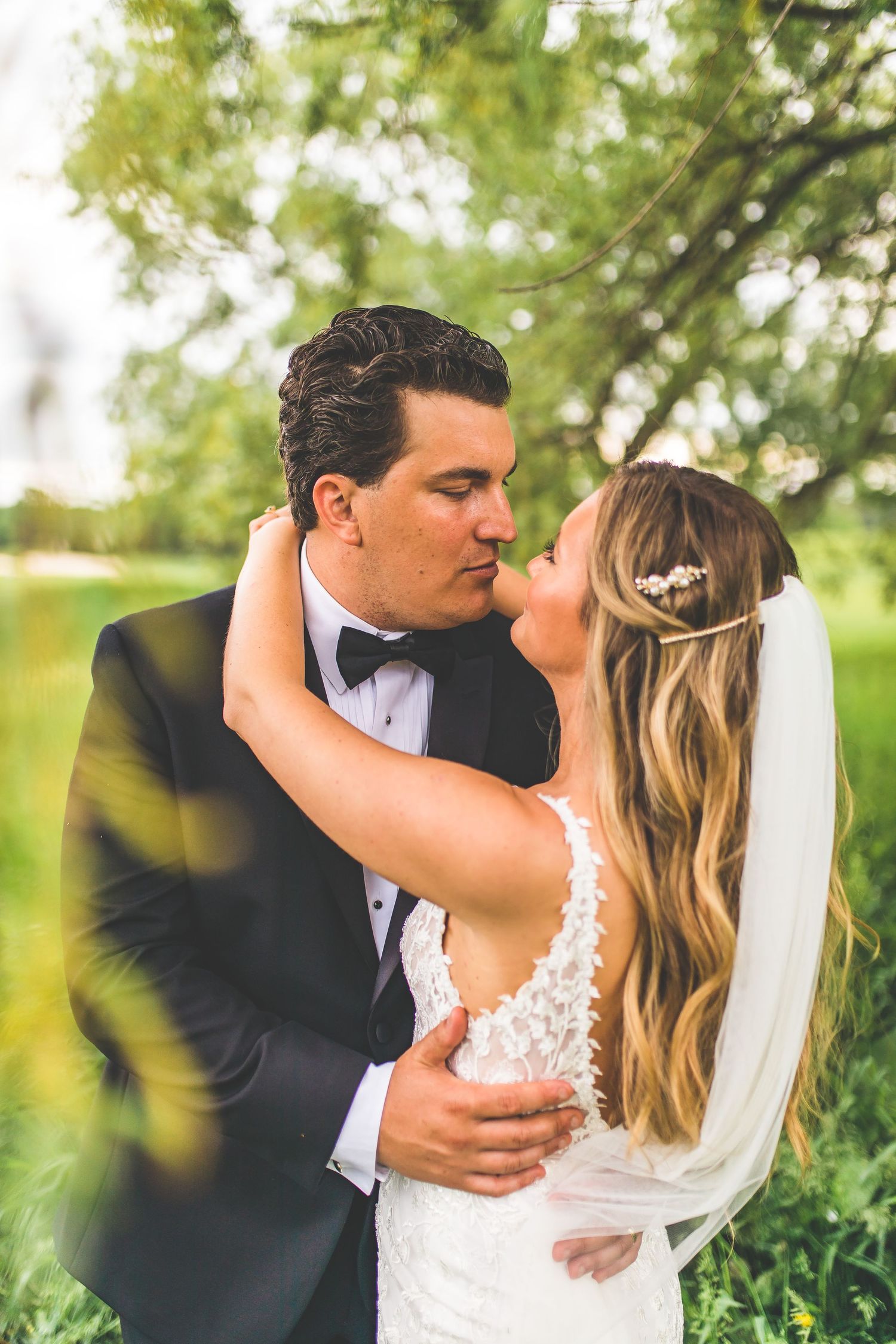Intimate wedding portraits showing couple embracing in lush garden setting.
