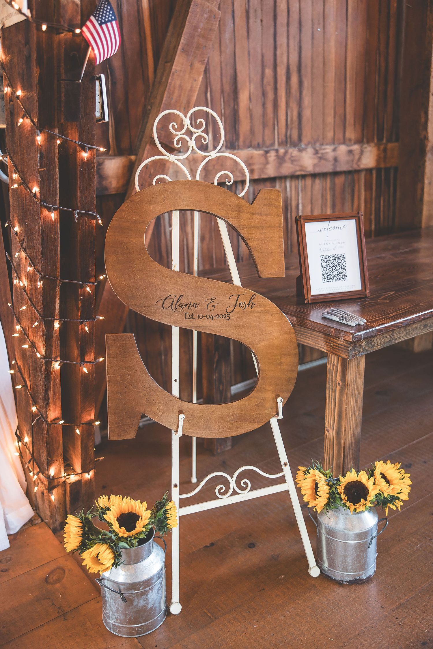 Wooden decorative signs with sunflowers and string lights at rustic wedding venue.