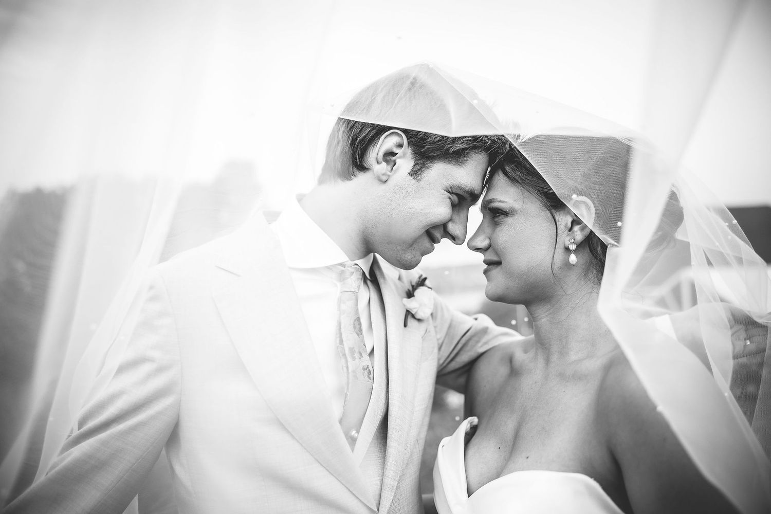 Black and white romantic portrait series of a couple under a flowing veil.