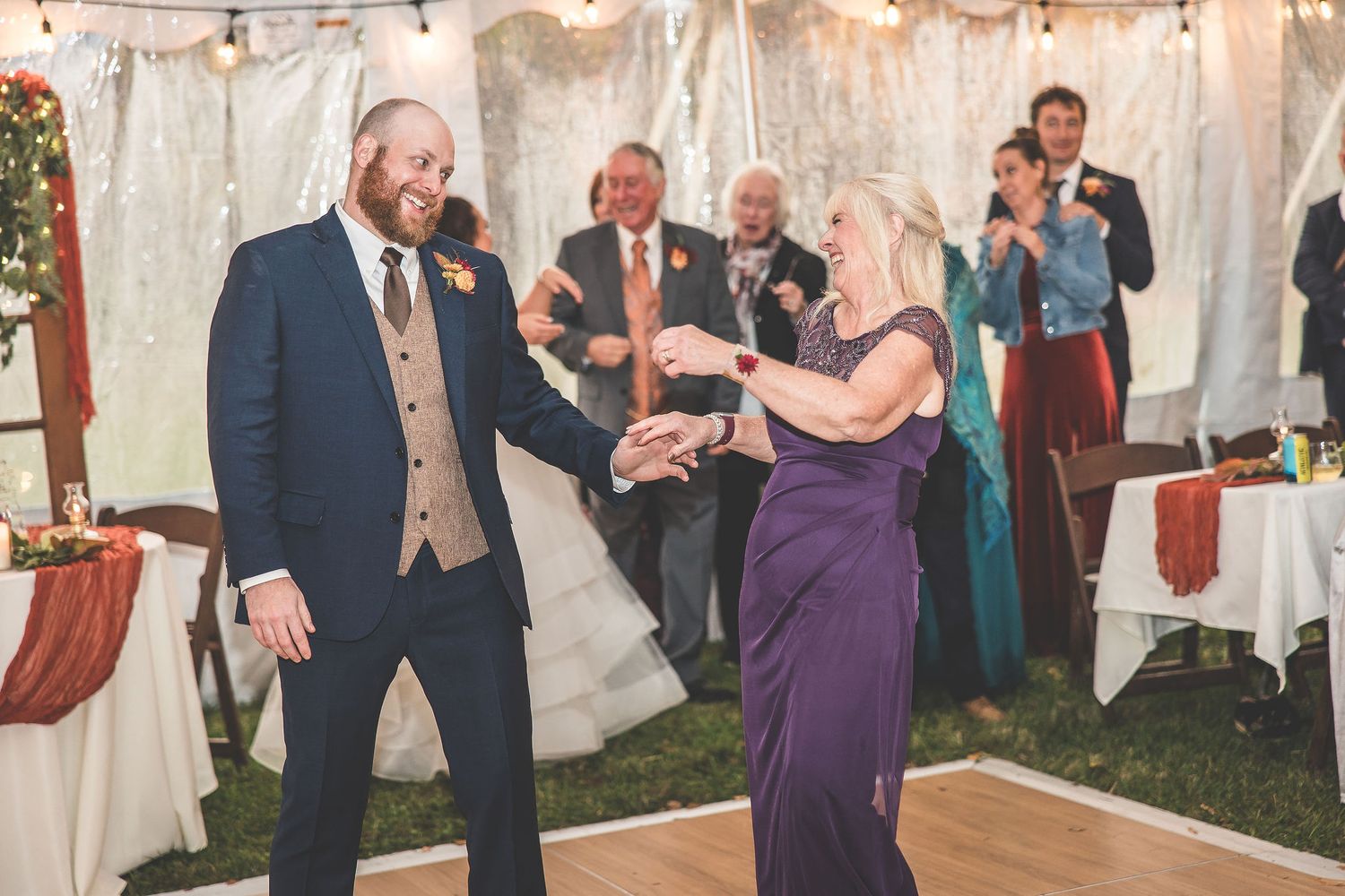 Guests enjoying a festive celebration under twinkling lights in an outdoor tent setting.