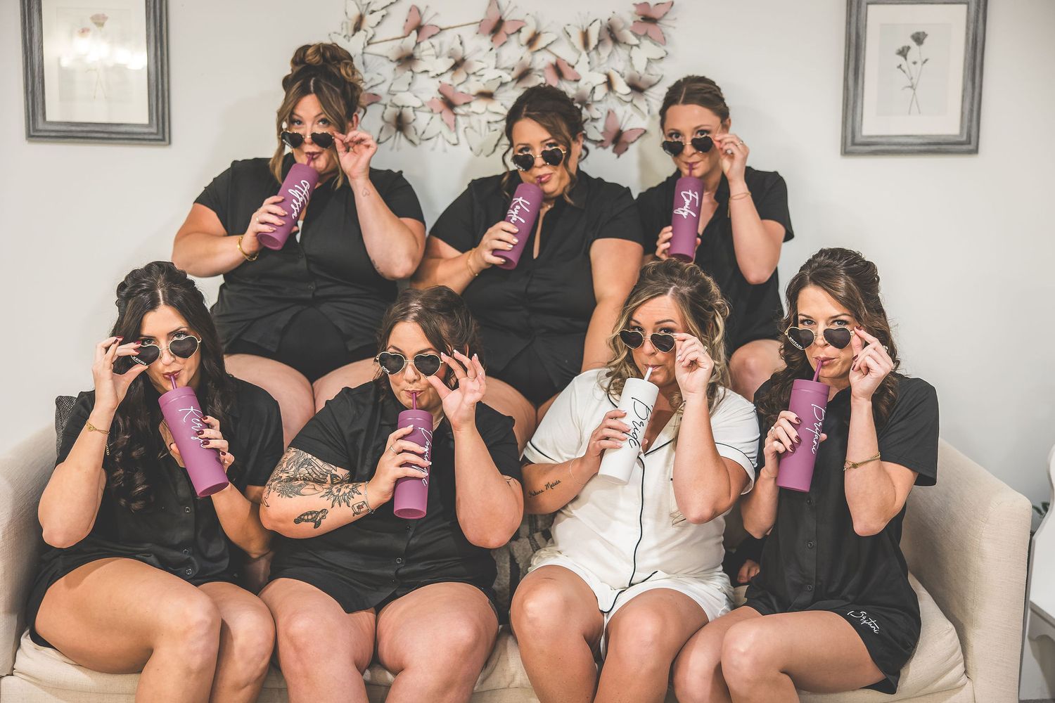 Group wearing matching black outfits sitting in row holding party noisemakers.