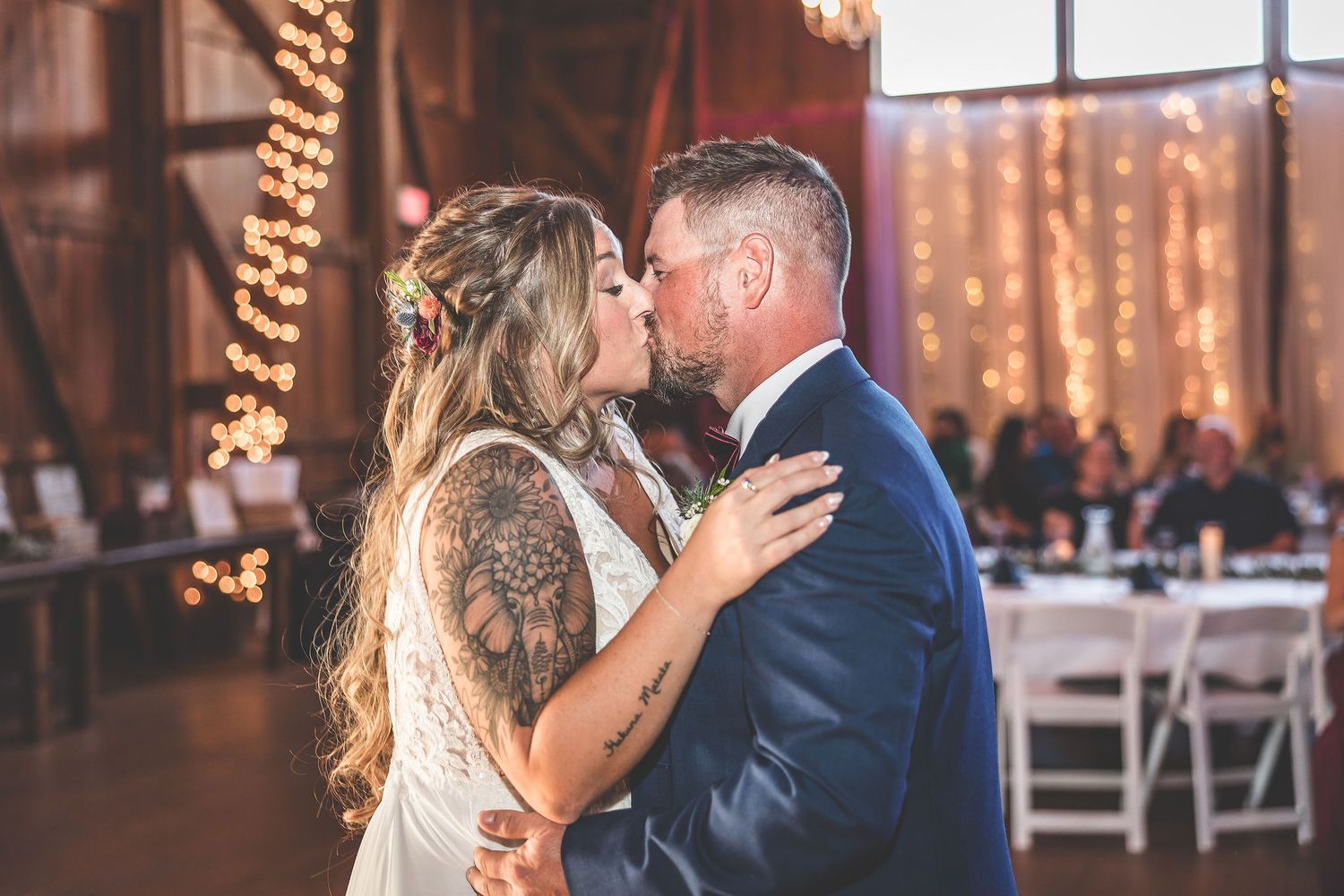 Intimate dance moment during barn wedding reception with romantic lighting and elegant white draping.