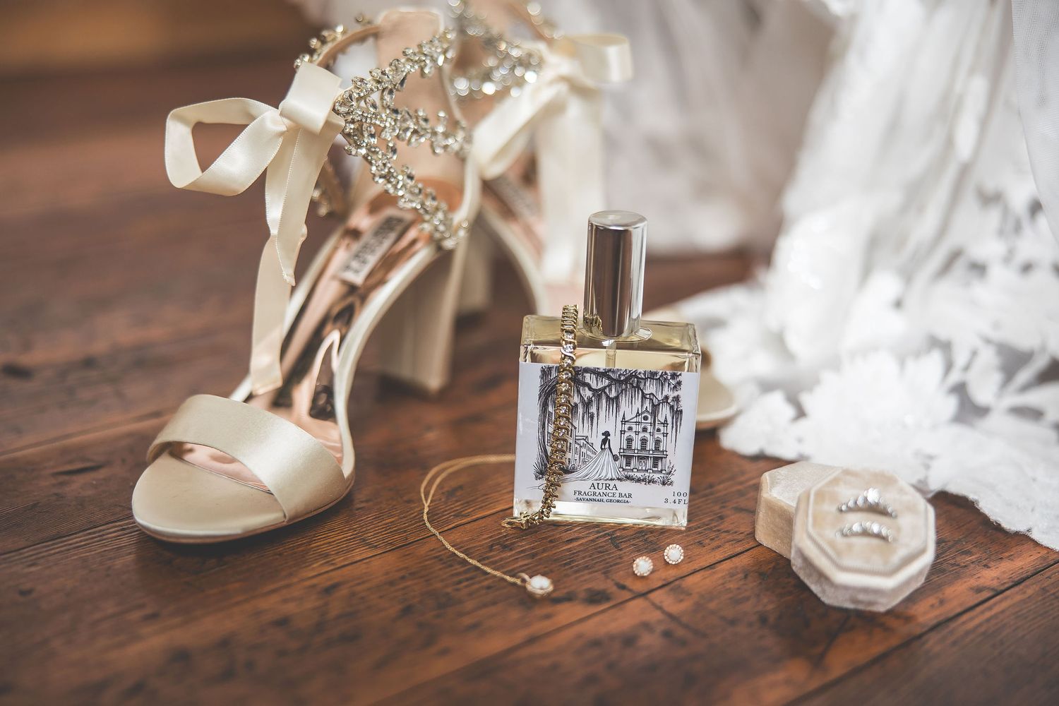 Wedding accessories including rings, shoes, and perfume bottles arranged on a rustic wooden surface.