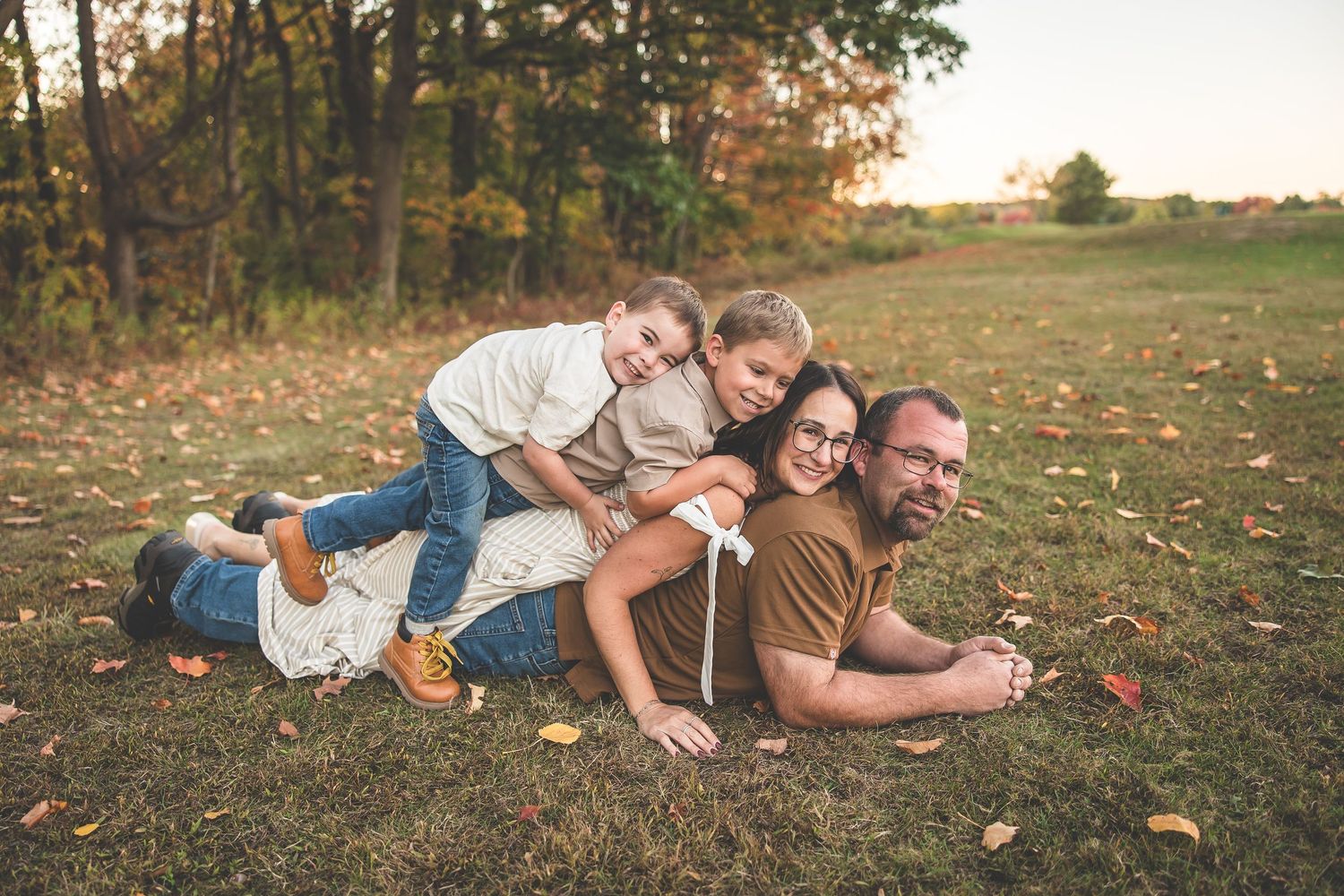 A family lies together on grass during a casual outdoor photo session.