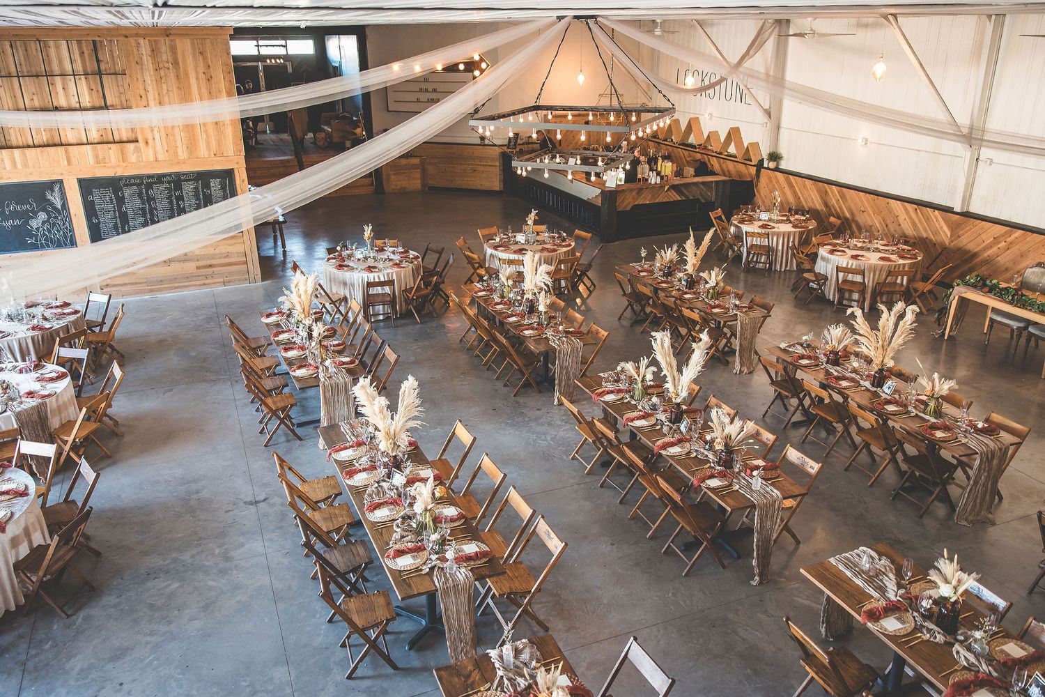 Wide angle view of an empty event space set up with wooden folding chairs and tables.