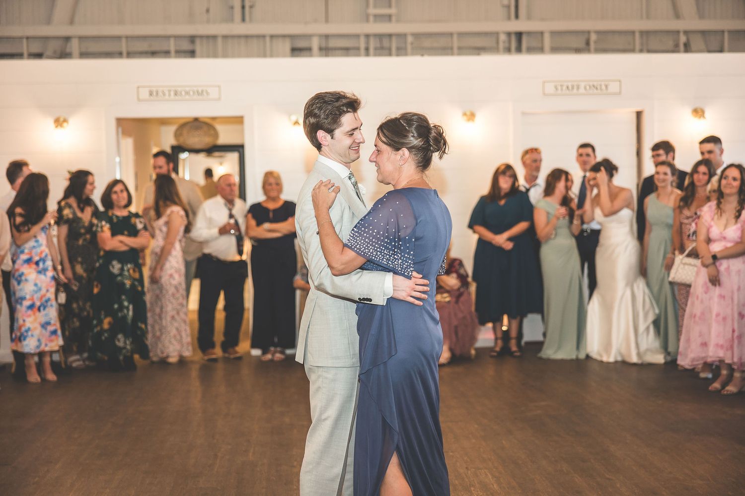 Wedding guests dance and celebrate on a spacious dance floor at an elegant indoor reception venue.
