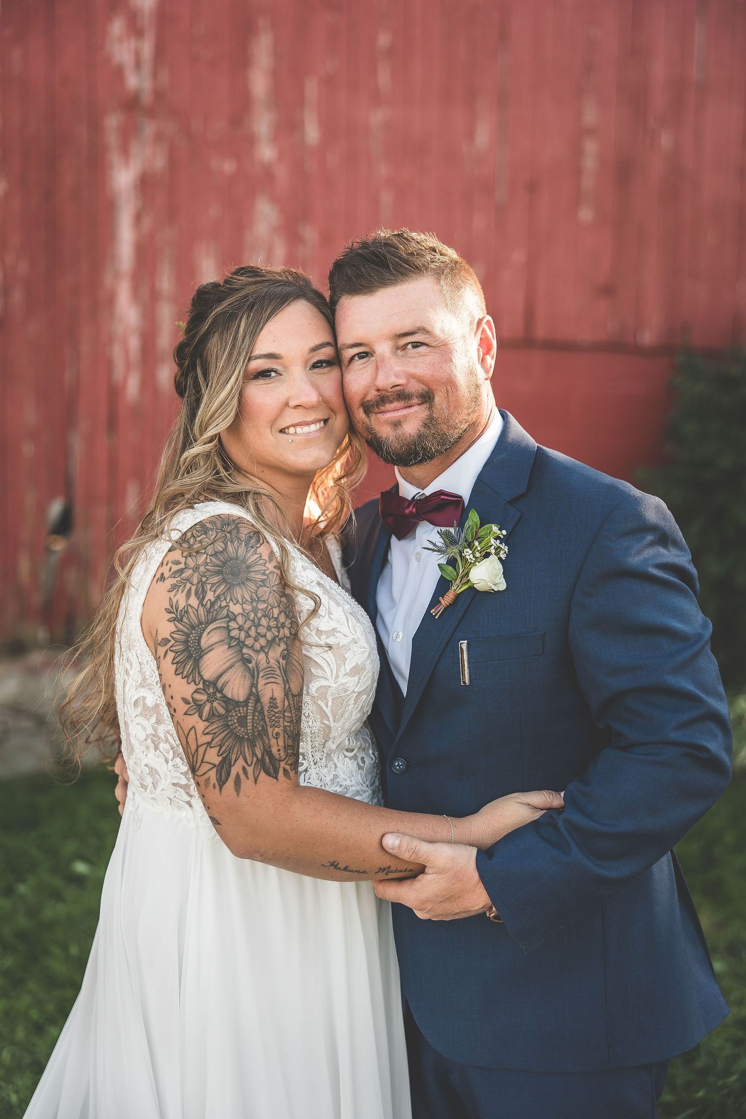 Intimate wedding portraits against rustic red barn backdrop during golden hour.