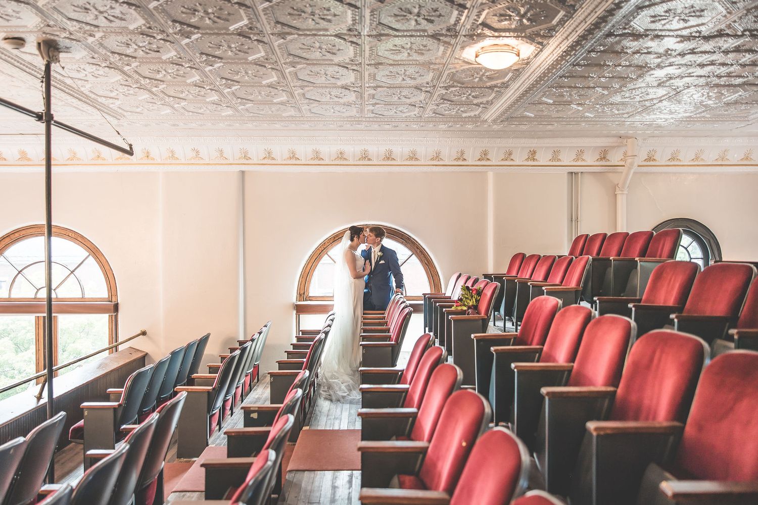Classic theater interior with red velvet seats and ornate ceiling details during a wedding photoshoot.