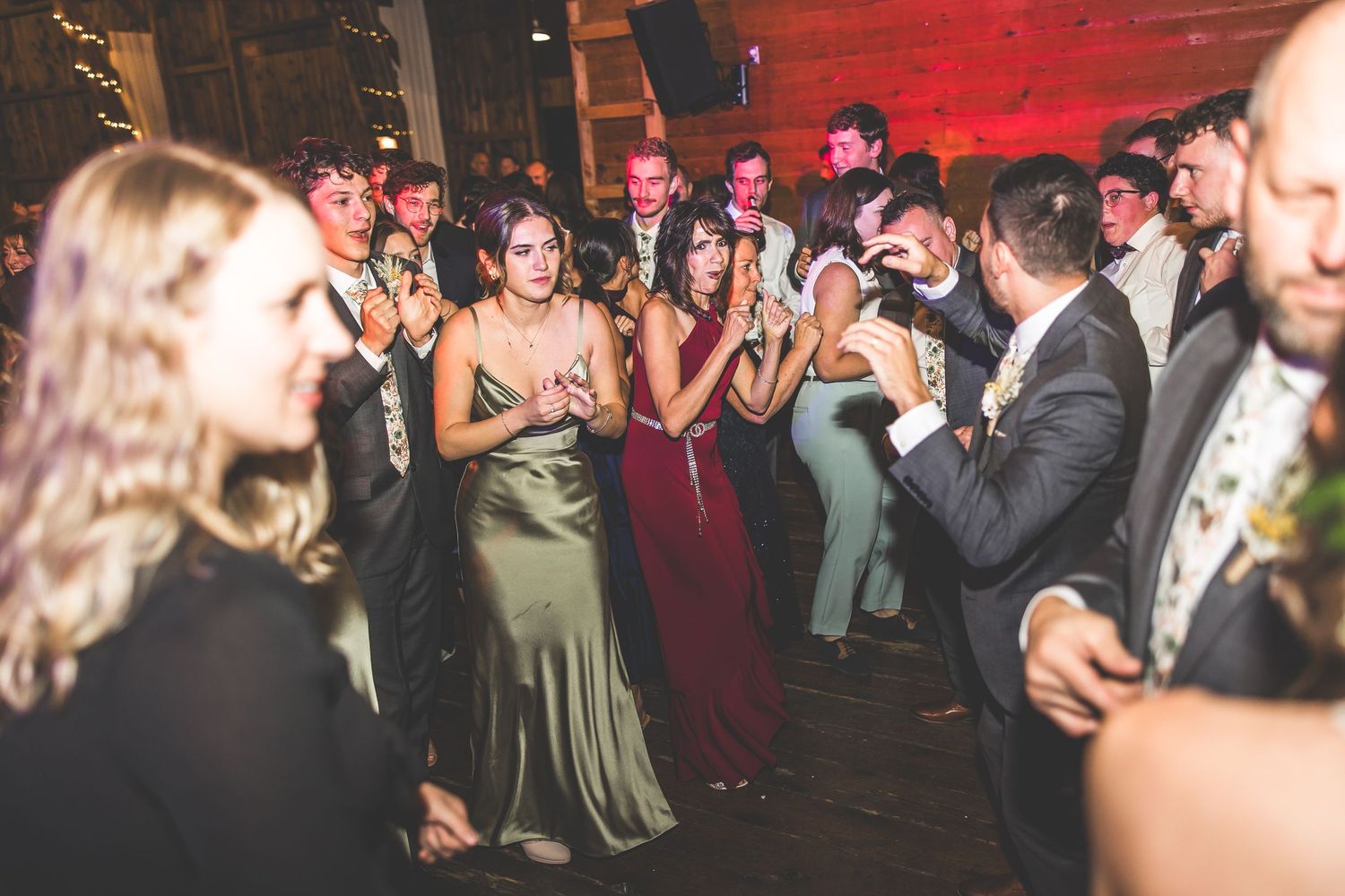 Lively dance floor at barn wedding reception with guests celebrating.