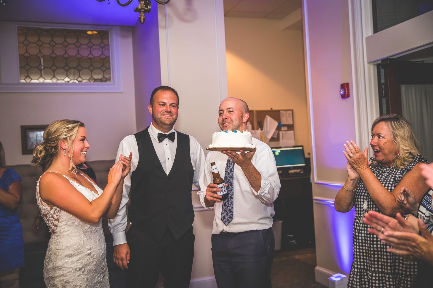 Wedding reception guests dancing and enjoying the celebration under purple lighting.
