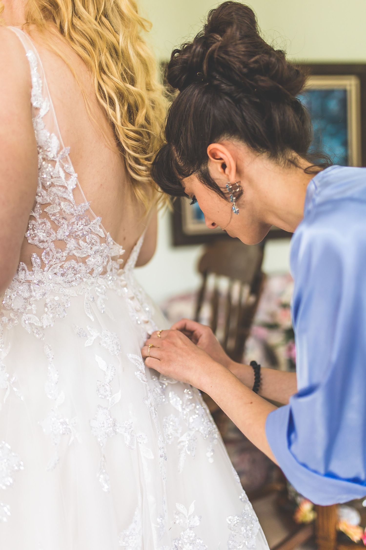 Close-up details of a white lace wedding dress being adjusted.
