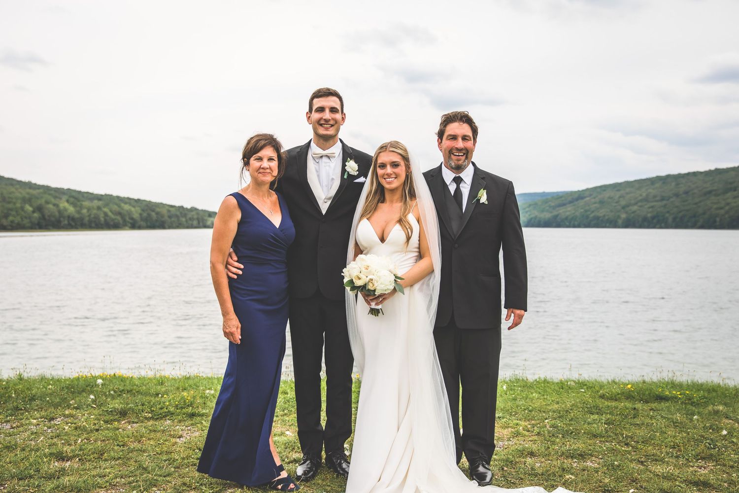 Family formal portraits taken at lakeside wedding with mountains in background.