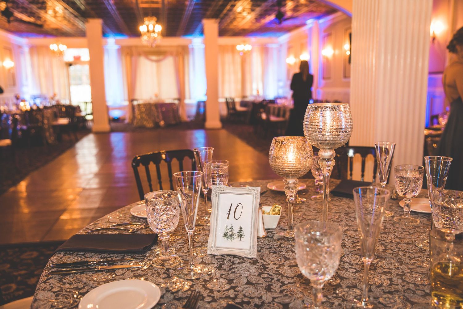 Luxurious reception hall with crystal chandeliers and purple uplighting creating a romantic atmosphere.
