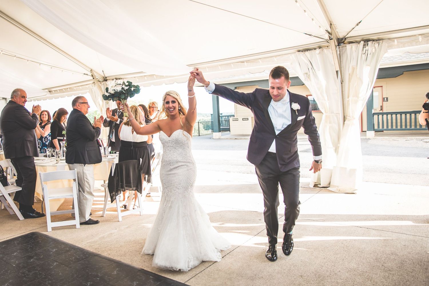 Wedding reception dancing and celebrations under a white tent.