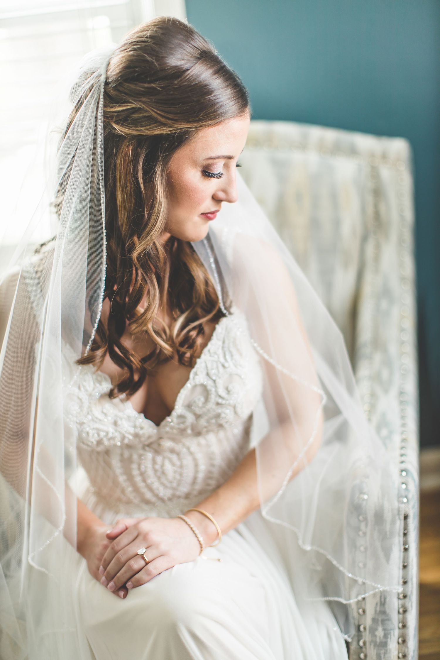An elegant bridal portrait showcasing a lace wedding gown and flowing veil.