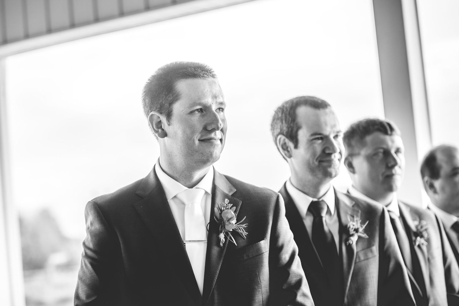Wedding party members lined up in formal attire during an indoor ceremony.